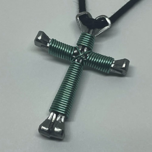 A small baby blue cross of nails necklace on a black cord.