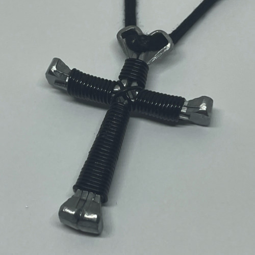 A small black cross of nails necklace on a black cord.