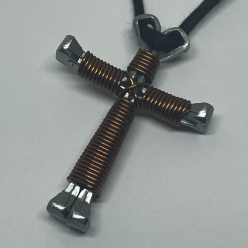A small brown cross of nails necklace on a black cord.