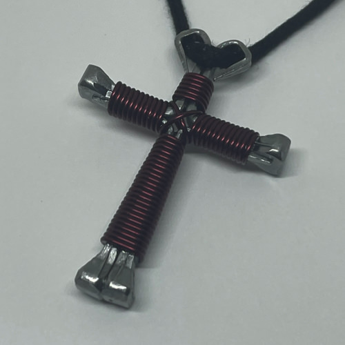 A small burgandy cross of nails necklace on a black cord.