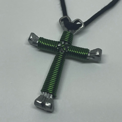 A small green cross of nails necklace on a black cord.