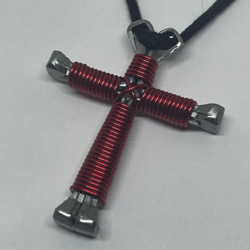 A small red cross of nails necklace on a black cord.