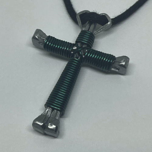 A small teal cross of nails necklace on a black cord.